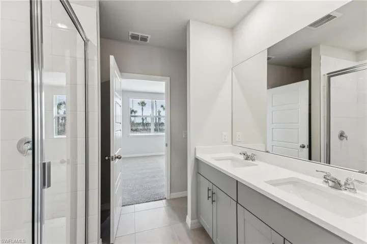 Bathroom featuring walk in shower, vanity, and tile patterned flooring