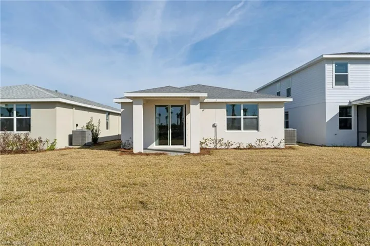 Back of house with cooling unit and a yard