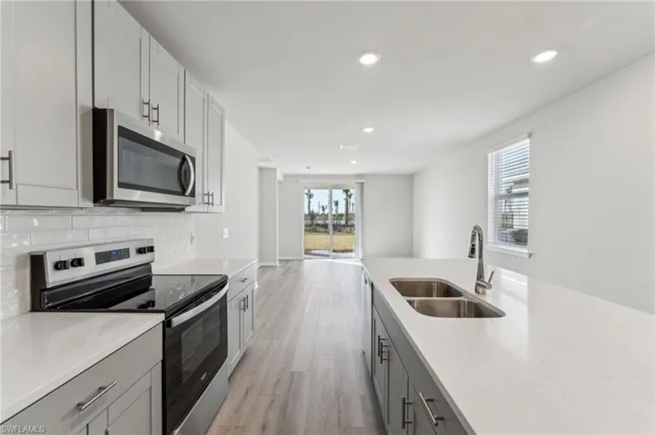 Kitchen with sink, gray cabinets, backsplash, stainless steel appliances, and light hardwood / wood-style floors