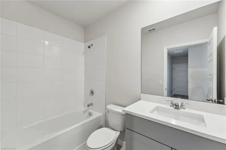 Full bathroom with vanity, tiled shower / bath combo, and toilet