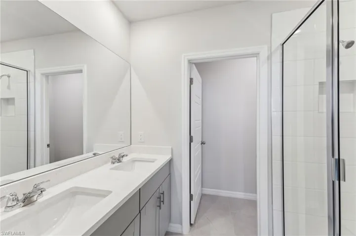 Bathroom with vanity, an enclosed shower, and tile patterned flooring