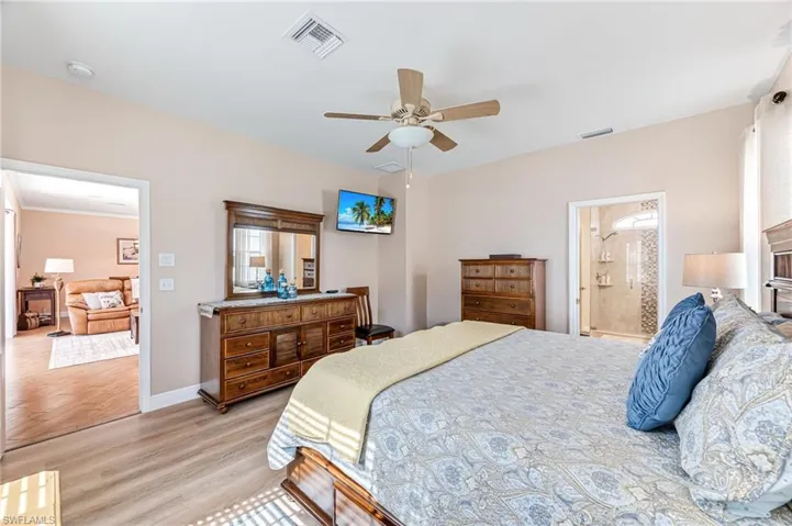 Bedroom with connected bathroom, ceiling fan, and light hardwood / wood-style flooring