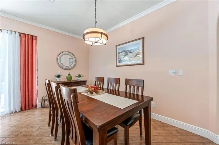 Dining space with light wood-type flooring and crown molding