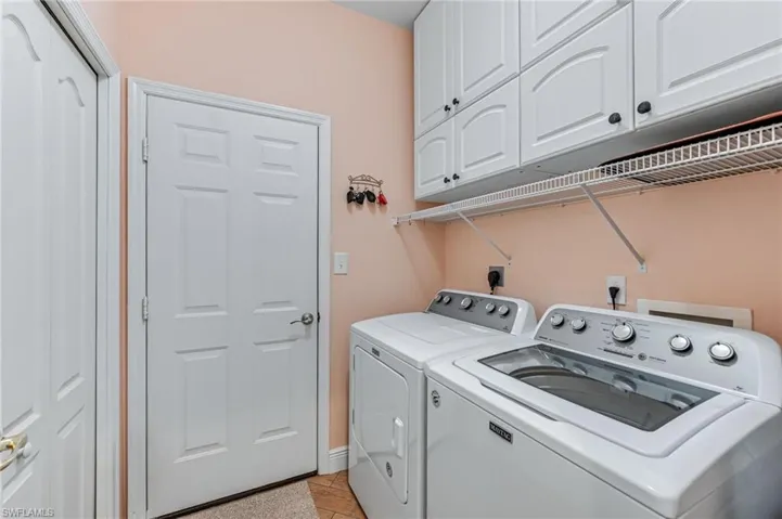 Washroom featuring washer and dryer, cabinets, and light tile patterned floors