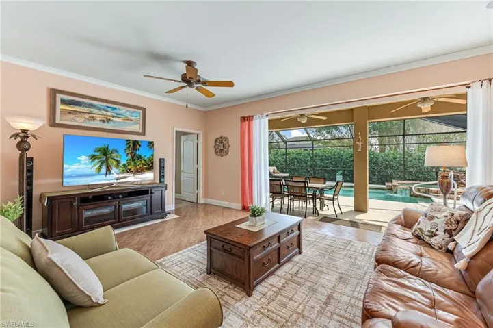 Living room with light hardwood / wood-style flooring, ceiling fan, and crown molding