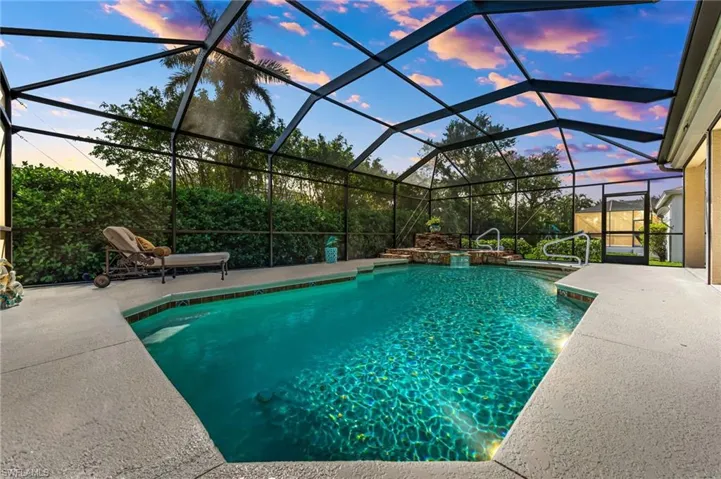 Pool at dusk featuring glass enclosure and a patio