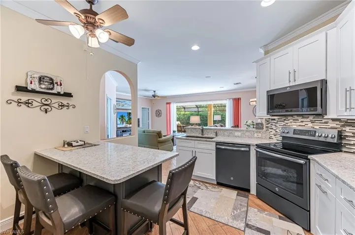 Kitchen featuring white cabinetry, a kitchen breakfast bar, light hardwood / wood-style flooring, kitchen peninsula, and appliances with stainless steel finishes