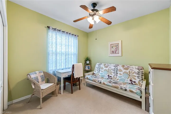 Living area featuring light colored carpet and ceiling fan
