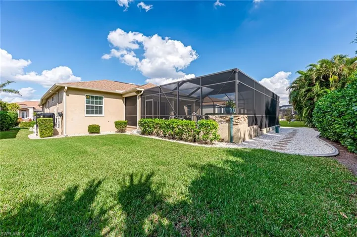 Rear view of property featuring a yard and glass enclosure