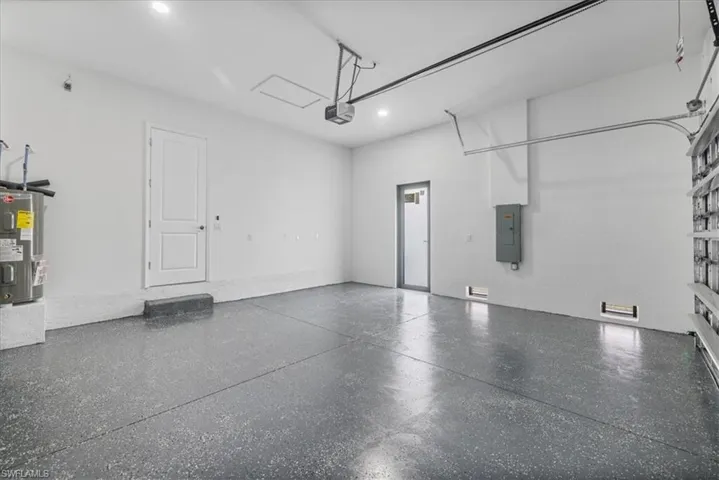 Garage featuring electric water heater and electric panel