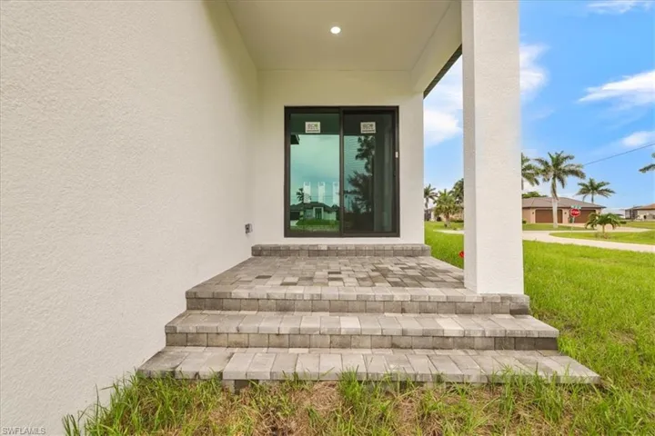 Entrance to property featuring stucco siding and a lawn