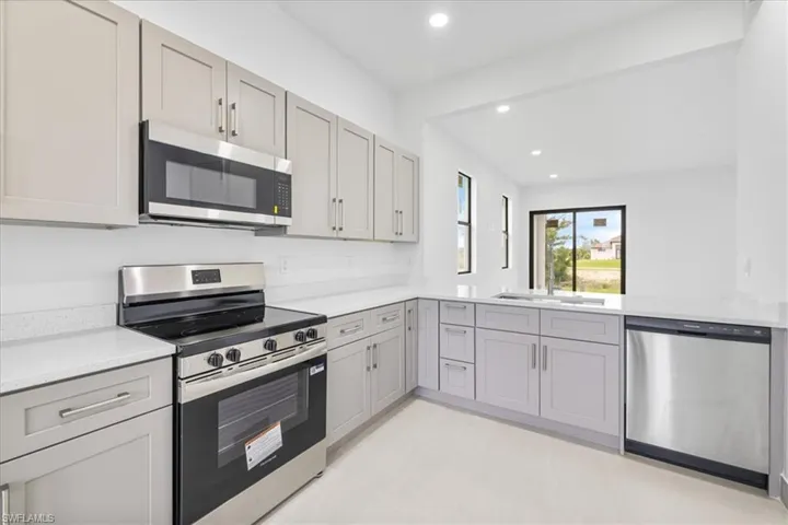 Kitchen with stainless steel appliances, gray cabinetry, recessed lighting, and light stone countertops