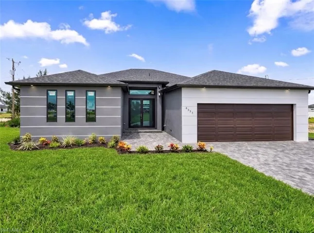 Contemporary home with french doors, a front lawn, a shingled roof, and decorative driveway
