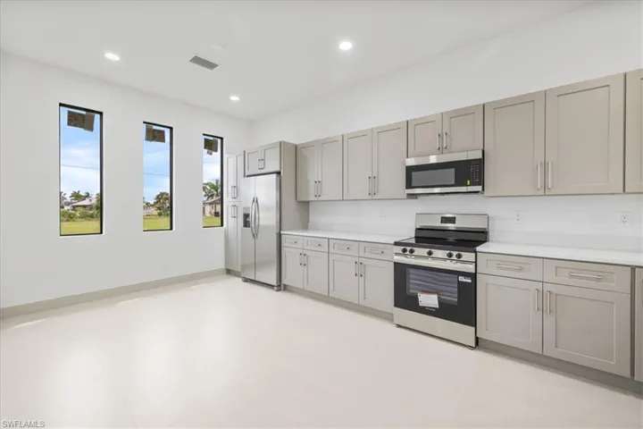 Kitchen with gray cabinetry, stainless steel appliances, and recessed lighting