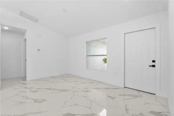 Spare room with vaulted ceiling and light marble finish floors