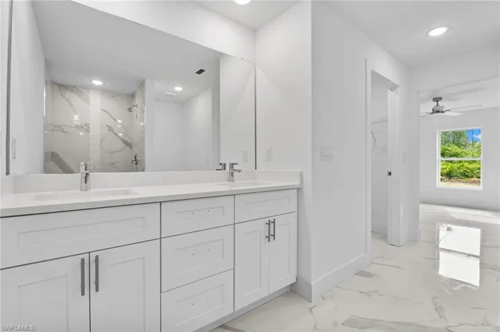 Full bathroom with double vanity, a marble finish shower, light marble finish floors, recessed lighting, and a spacious closet