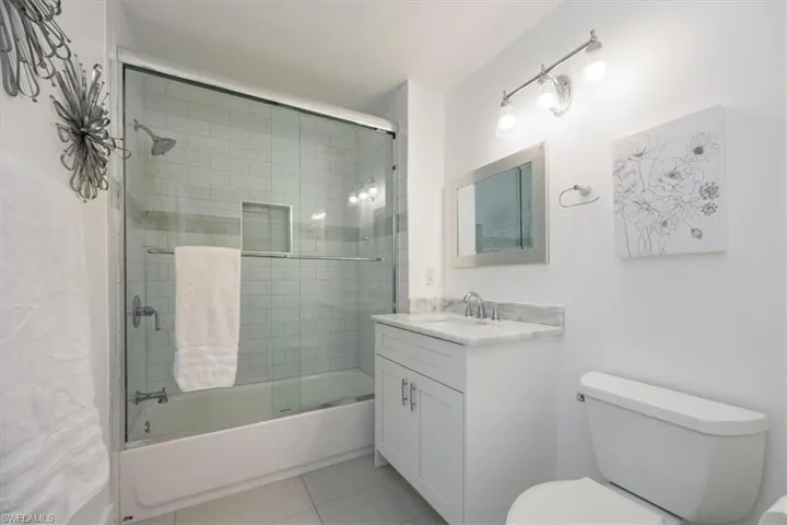 Bathroom featuring enclosed tub / shower combo, vanity, and light tile patterned floors