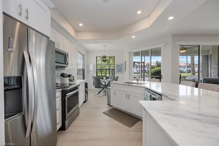 Kitchen with white cabinets, stainless steel appliances, light stone counters, recessed lighting, and hanging light fixtures