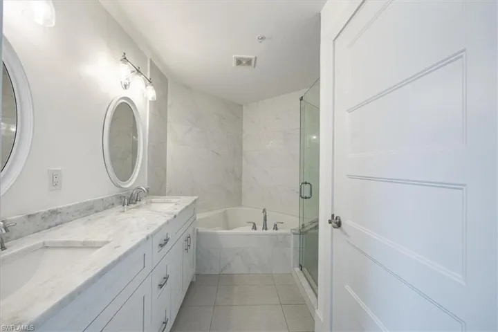 Full bath with a garden tub, a shower stall, double vanity, and light tile patterned flooring