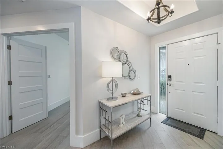 Entryway with a chandelier, light wood-type flooring, and a raised ceiling