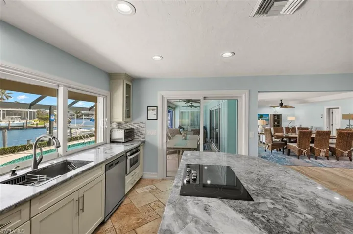 Kitchen featuring light stone counters, stainless steel appliances, recessed lighting, glass insert cabinets, and a water view