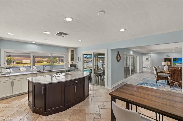 Kitchen featuring light stone countertops, recessed lighting, dark brown cabinets, a textured ceiling, and stone tile floors