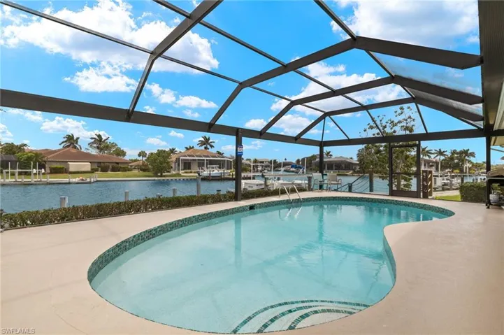 Swimming pool featuring boat lift, a boat dock, a water view, and a lanai