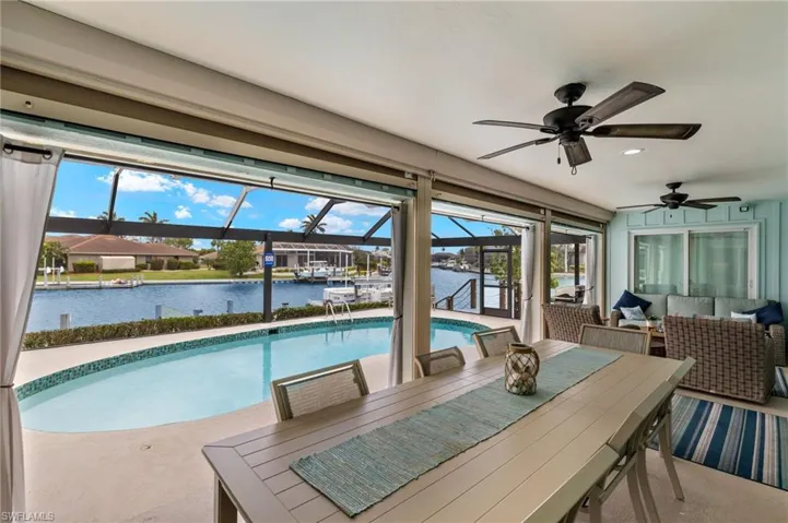 Outdoor pool with a lanai, a water view, a sunroom, outdoor dining area, and a patio area