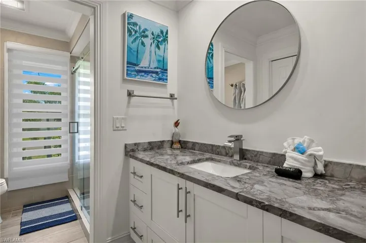 Full bathroom featuring vanity, crown molding, a stall shower, and light wood-style floors