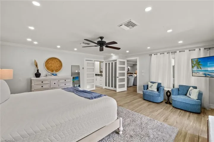 Bedroom featuring light wood-style flooring, ornamental molding, recessed lighting, a ceiling fan, and ensuite bath