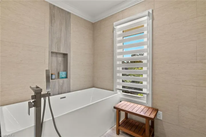 Bathroom featuring a freestanding bath and crown molding