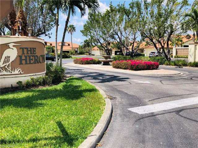 Community entrance featuring a monument sign, tropical landscaping, and a central roundabout with fountain