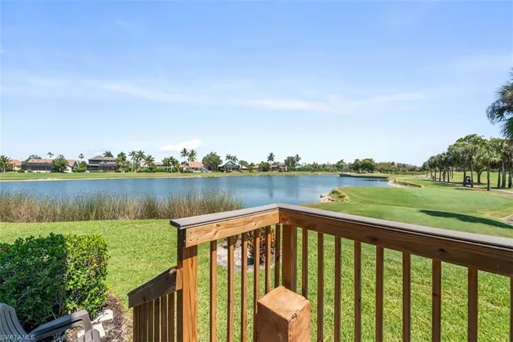 Expansive outdoor area featuring a wooden railing, manicured lawn, and mature landscaping
