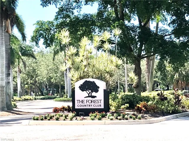 Entrance sign for The Forest Country Club, featuring a white arch with black lettering and a tree silhouette