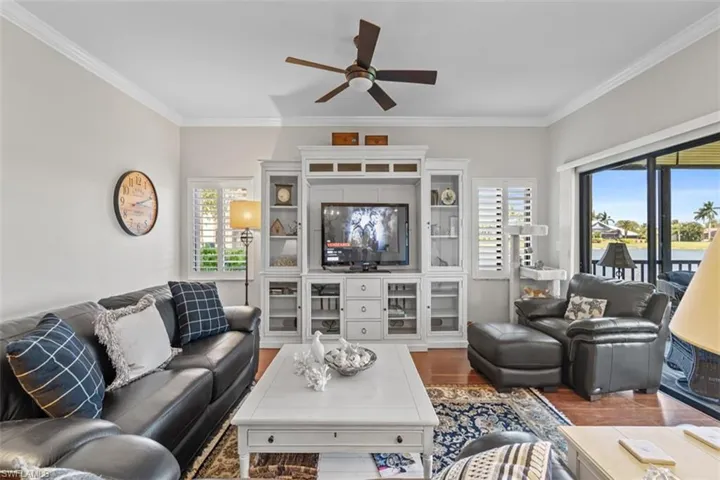 Spacious living area featuring crown molding, wood-finish flooring, and a large built-in entertainment center