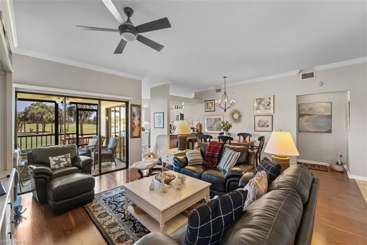 Spacious living area featuring wood-finish flooring, a ceiling fan, and crown molding