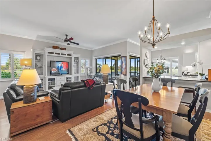 Open-concept living space featuring wood-finish flooring, plantation shutters, and a built-in entertainment center