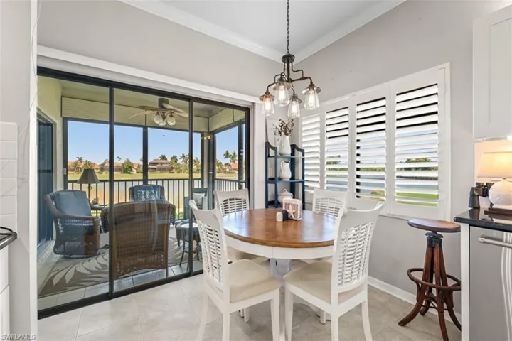Screened lanai with ceiling fan and water views, featuring tile flooring and a black metal railing