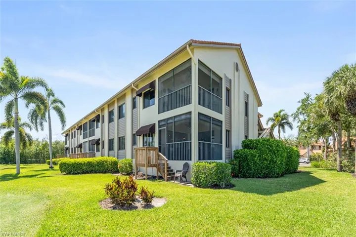 Multi-story building featuring screened balconies, awnings, and a tiled roof