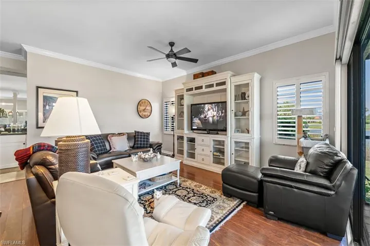 Living area featuring wood-finish flooring, a ceiling fan, and crown molding