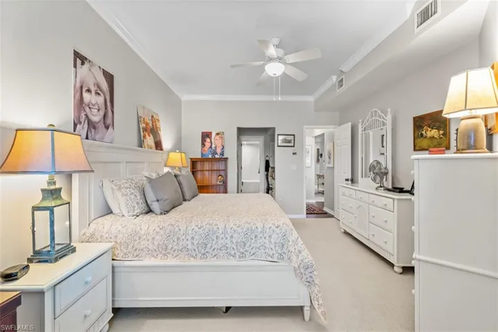 Spacious master Bedroom featuring light-toned walls, crown molding, a ceiling fan, and carpeted flooring