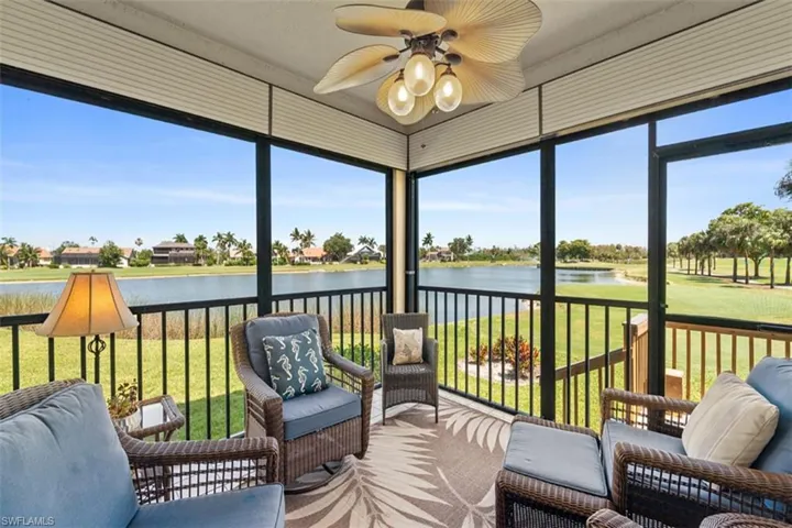 Screened lanai featuring a ceiling fan with integrated lighting, a patterned area rug, and a scenic water and golf course backdrop