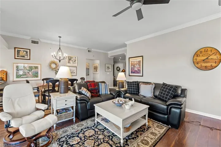 Open-concept living space featuring wood-finish flooring, crown molding, and recessed lighting