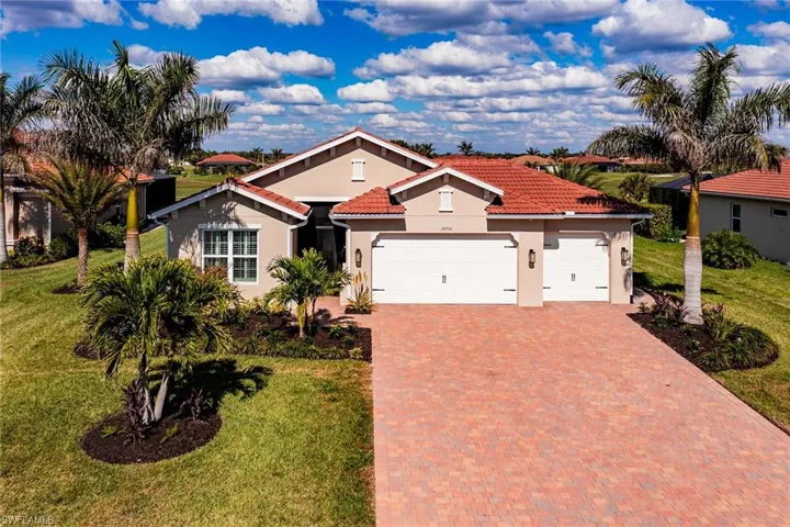Mediterranean / spanish house with a tiled roof, a front lawn, decorative driveway, and an attached garage
