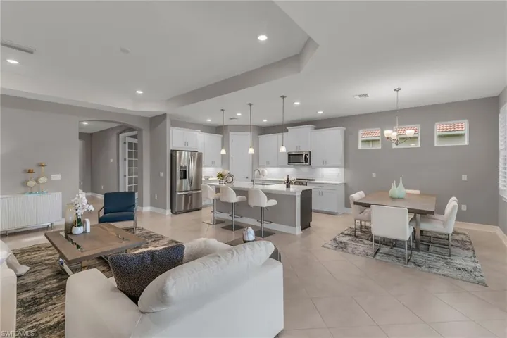 Living room featuring arched walkways, light tile patterned floors, visible vents, and recessed lighting