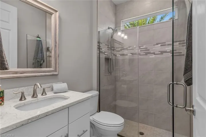 Bathroom with vanity, a shower stall, and toilet