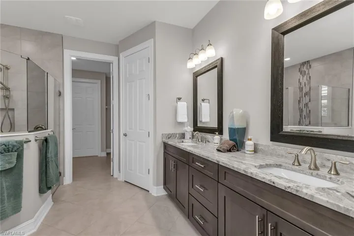 Full bath featuring baseboards, double vanity, a sink, and a shower stall