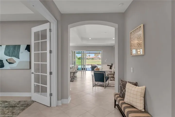Hallway featuring arched walkways, light tile patterned flooring, and baseboards