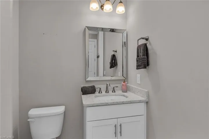 Half bathroom featuring vanity, toilet, and a notable chandelier