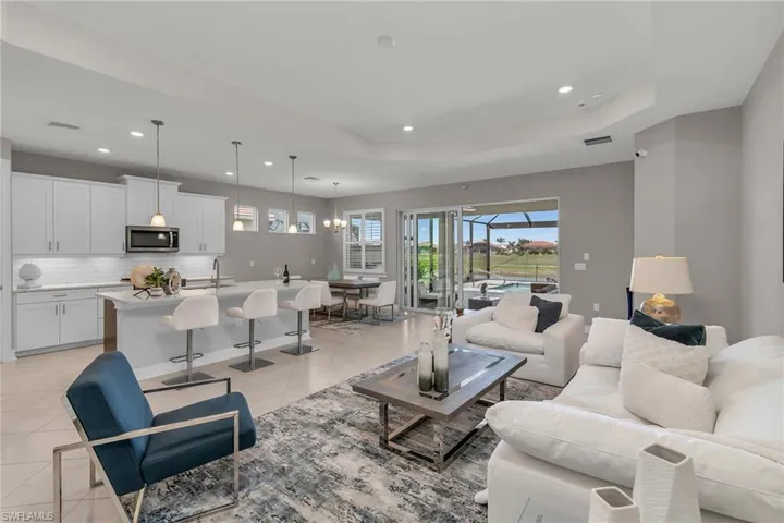 Living room with light tile patterned floors, a raised ceiling, visible vents, and recessed lighting